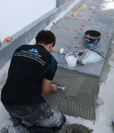 Tradepreson applying addesive before Installing Pavers at Porch in Melbourne