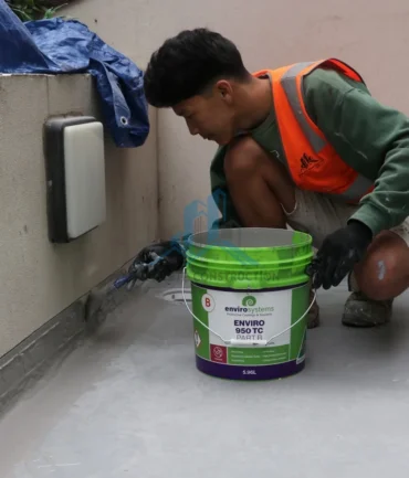 Worker applying balcony waterproofing membrane