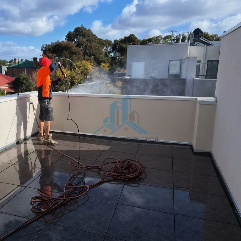 Worker pressure washing rooftop terrace